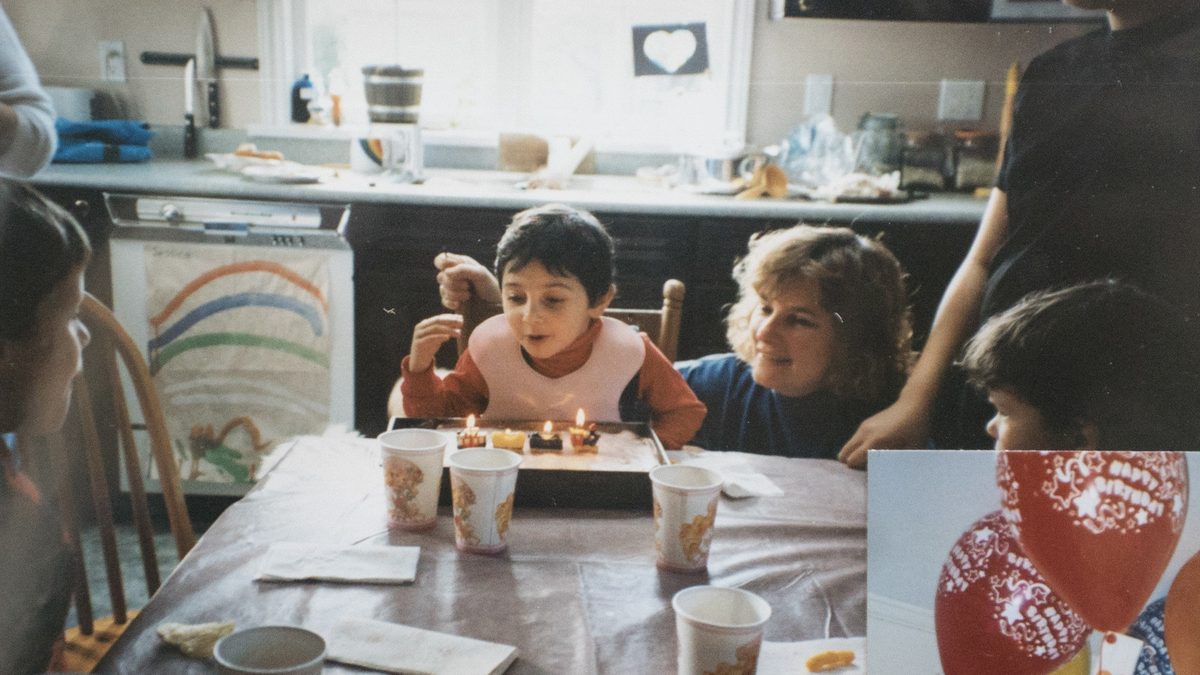 A child blowing out candles at a kitchen table