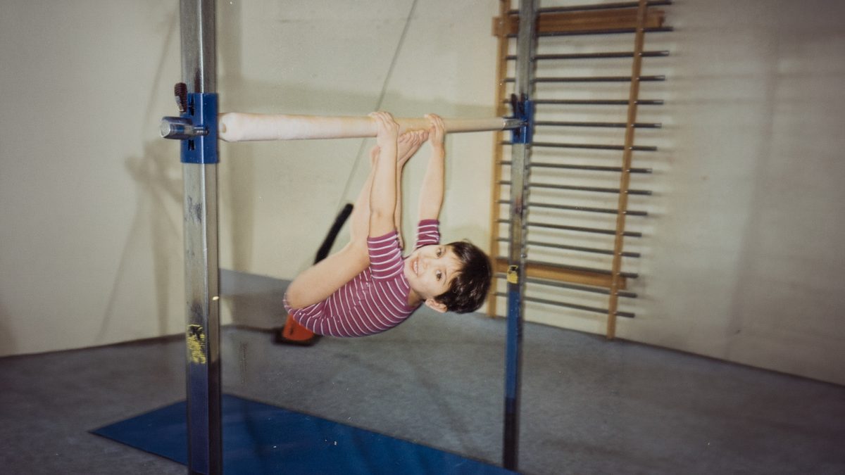 A girl hanging from a gymnastics bar