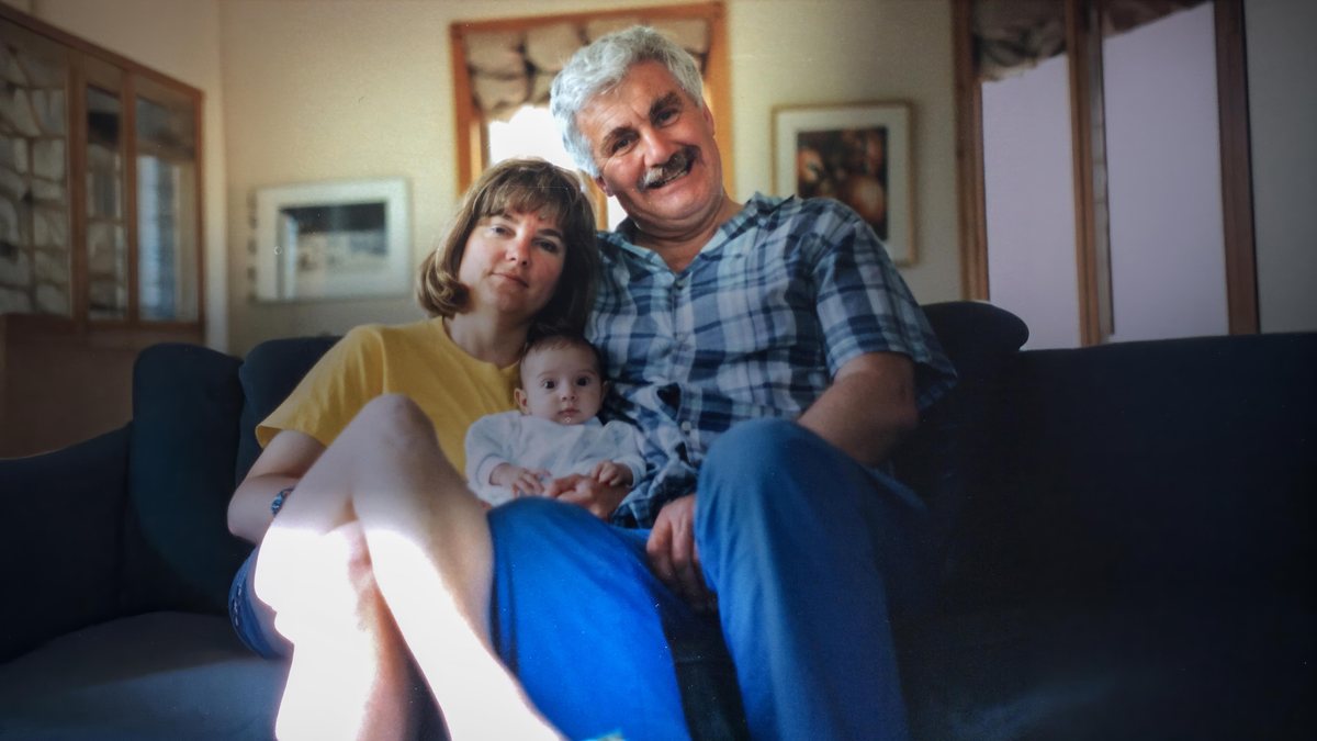 A woman and a man on a sofa holding a baby