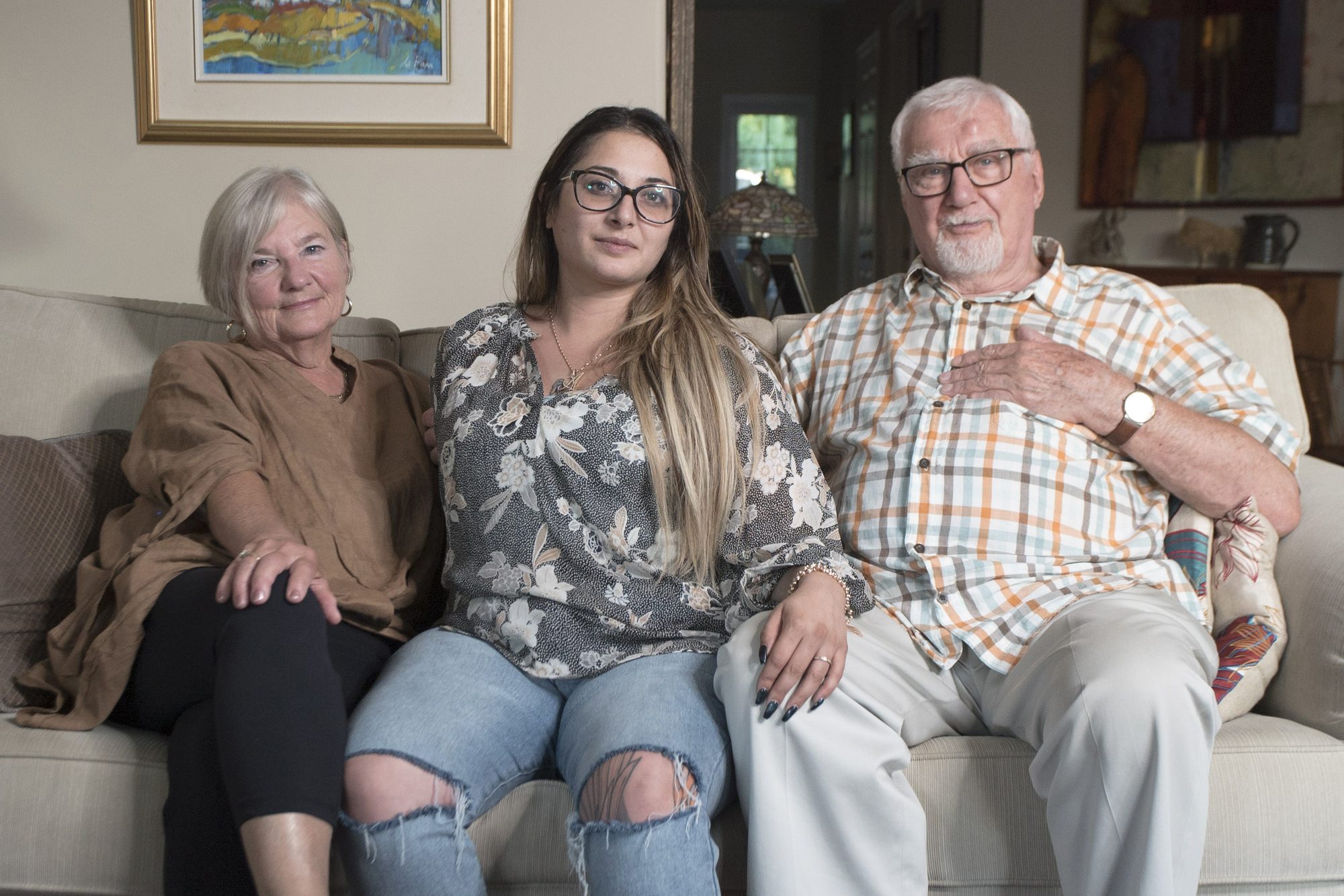 Jessi seated between her adoptive parents in their home in Canada